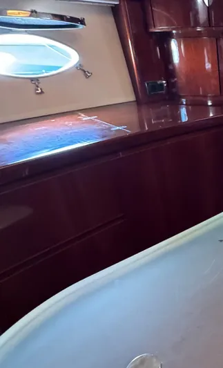  Yacht Photos Pics Interior of a 2004 Princess V65 yacht with polished wood and a porthole window.