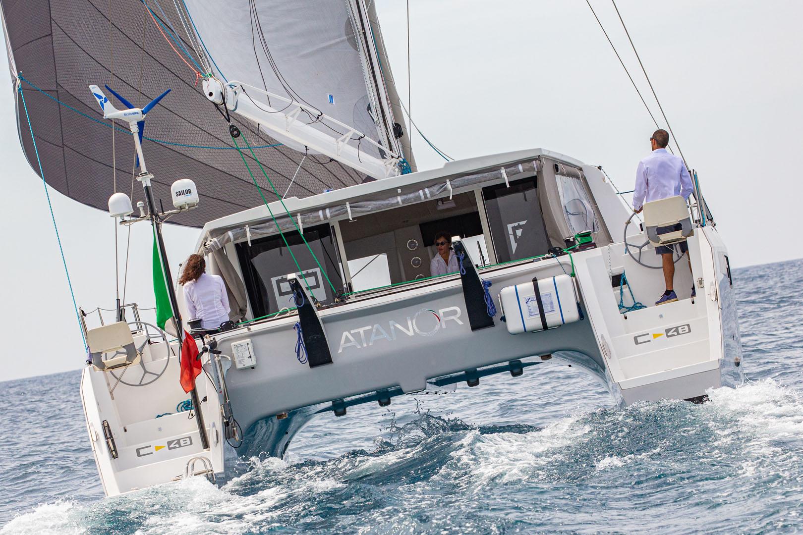 2025 Comar C-Cat 48 sailing catamaran on open sea with crew onboard.