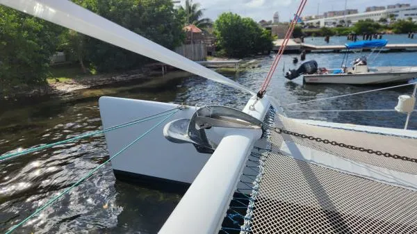Fat Cat Yacht Photos Pics Catamaran deck with rigging, Custom Morelli-Miller 1991, docked near lush greenery and calm waters.