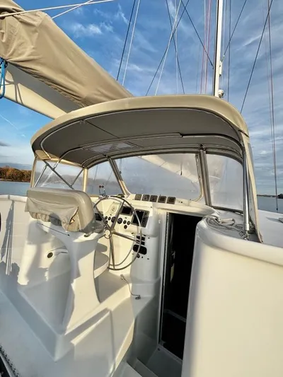 Fat Cat Yacht Photos Pics Cockpit of 1991 Custom Morelli-Miller sailboat with steering wheel and canopy under blue sky.