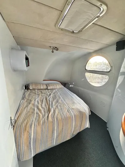 Fat Cat Yacht Photos Pics Compact 1991 Morelli-Miller custom interior with bed, round window, and striped bedding.