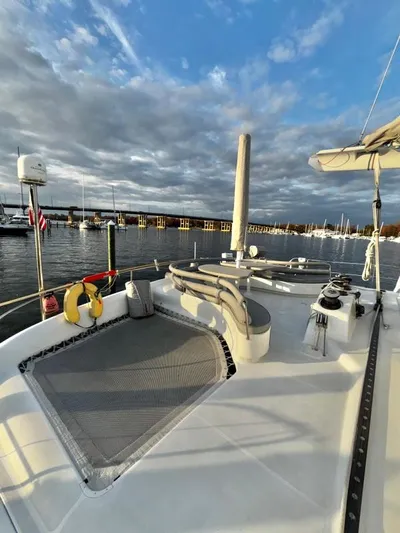 Fat Cat Yacht Photos Pics Catamaran deck with seating, netting, and marina view under cloudy sky. Custom Morelli-Miller, 1991.