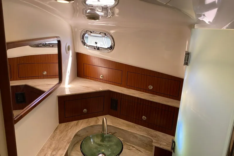 Yacht Photos Pics Luxurious bathroom interior of 2018 Pursuit OS 385 Offshore boat with wood accents and glass sink.