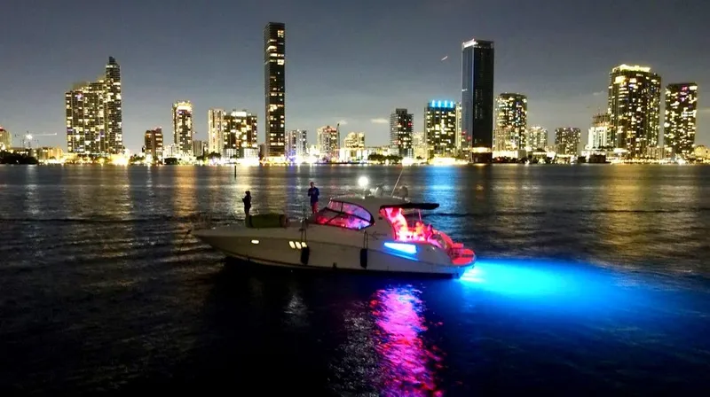  Yacht Photos Pics 2007 Sea Ray 44 Sundancer yacht illuminated on water, city skyline at night.