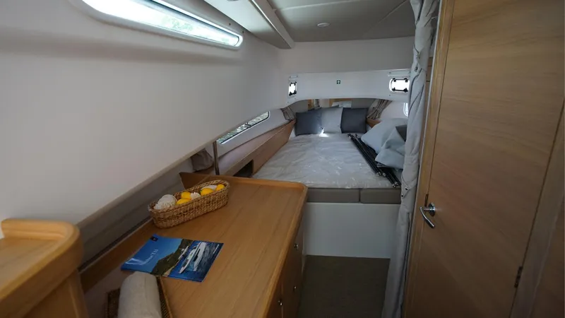 In-stock 2024 Nimbus T11 #260 Yacht Photos Pics 2024 Nimbus Tender 11 #260 cabin interior with bed, wooden furnishings, and natural light.