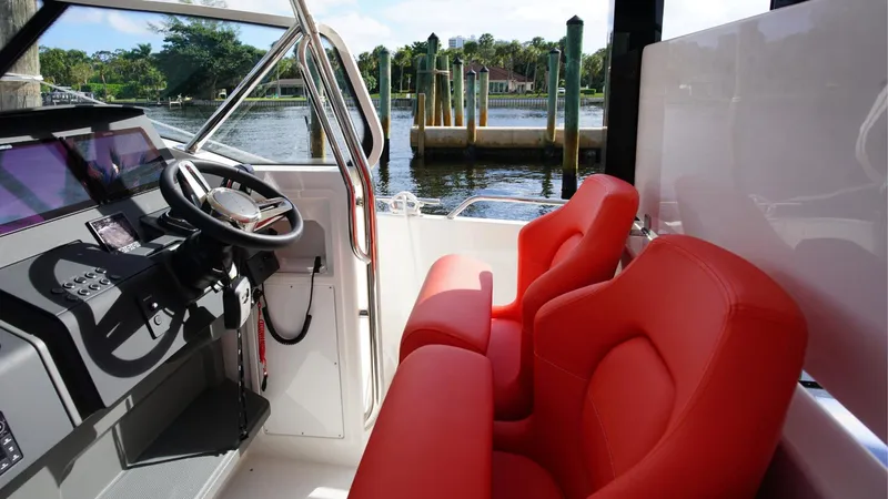 In-stock 2024 Nimbus T11 #260 Yacht Photos Pics 2024 Nimbus Tender 11 #260 with red seats and sleek dashboard, docked by the water.