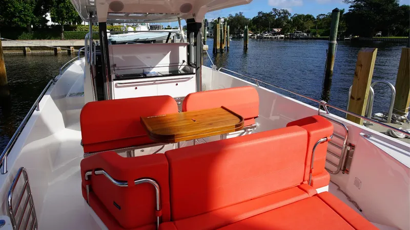 In-stock 2024 Nimbus T11 #260 Yacht Photos Pics 2024 Nimbus Tender 11 #260 with red seating and wooden table, docked by the water.