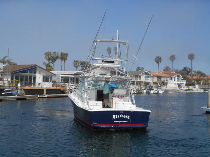 Mistress Yacht Photos Pics 1998 Cabo 31 Express boat docked in a marina with waterfront homes and palm trees.