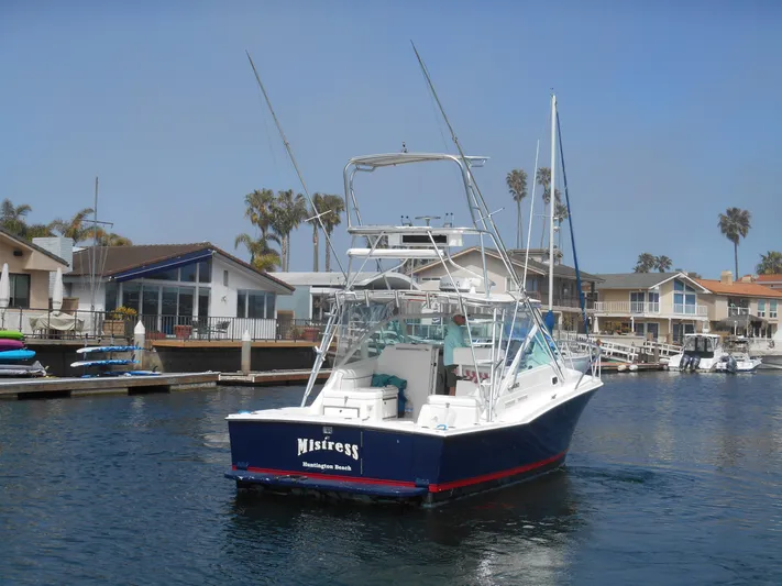 Mistress Yacht Photos Pics 1998 Cabo 31 Express boat docked in a marina with coastal homes in the background.
