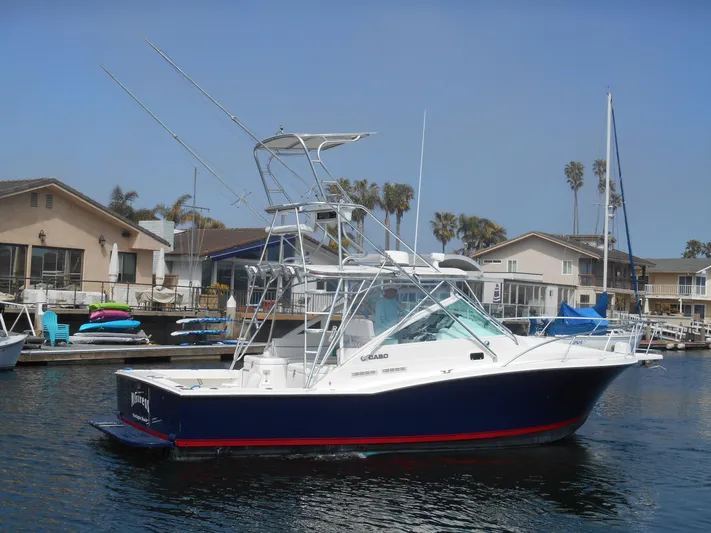 Mistress Yacht Photos Pics 1998 Cabo 31 Express boat docked in a marina, surrounded by waterfront homes.