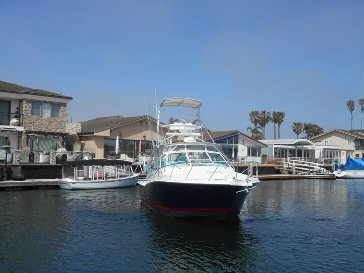 Mistress Yacht Photos Pics 1998 Cabo 31 Express boat docked in a marina with waterfront homes.