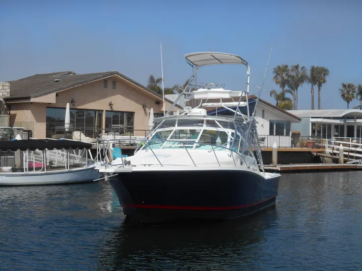 Mistress Yacht Photos Pics 1998 Cabo 31 Express boat docked near waterfront homes.