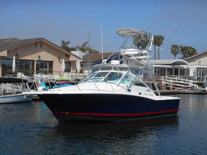 Mistress Yacht Photos Pics 1998 Cabo 31 Express boat docked in a marina, featuring a sleek design and flybridge.