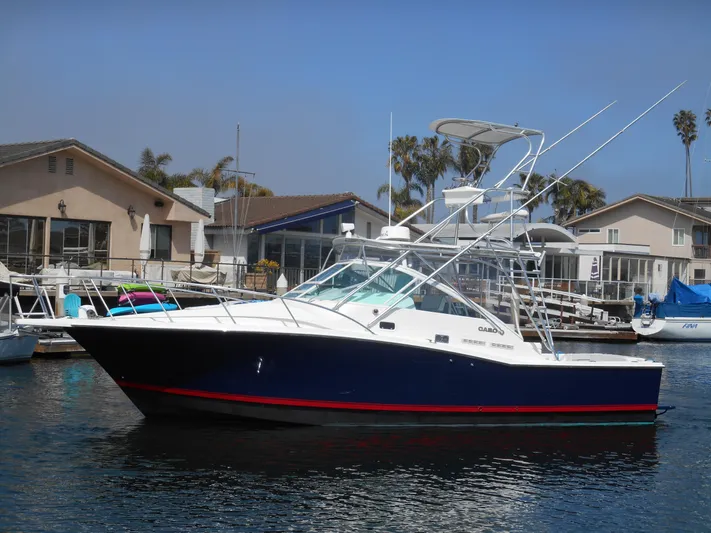 Mistress Yacht Photos Pics 1998 Cabo 31 Express boat docked near waterfront homes.