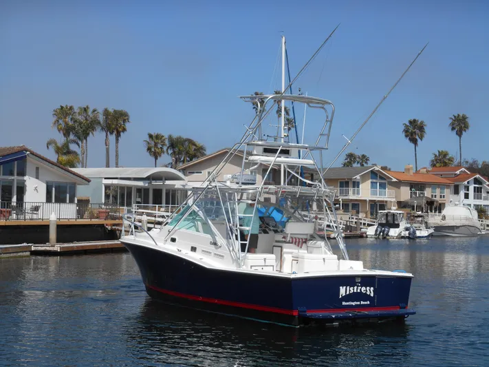 Mistress Yacht Photos Pics 1998 Cabo 31 Express boat docked near waterfront homes.