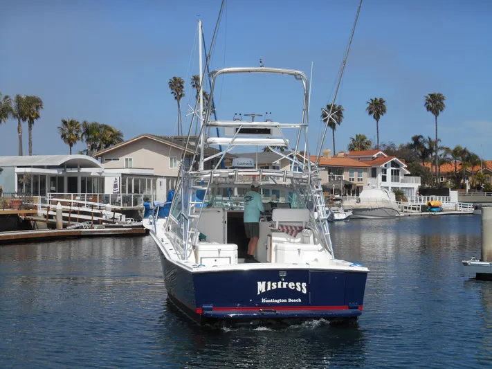 Mistress Yacht Photos Pics 1998 Cabo 31 Express boat in marina, palm trees, and waterfront homes in background.
