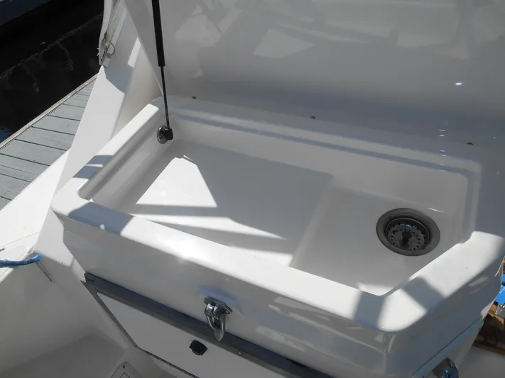 Mistress Yacht Photos Pics 1998 Cabo 31 Express boat sink with storage compartment, open lid, and drain plug.