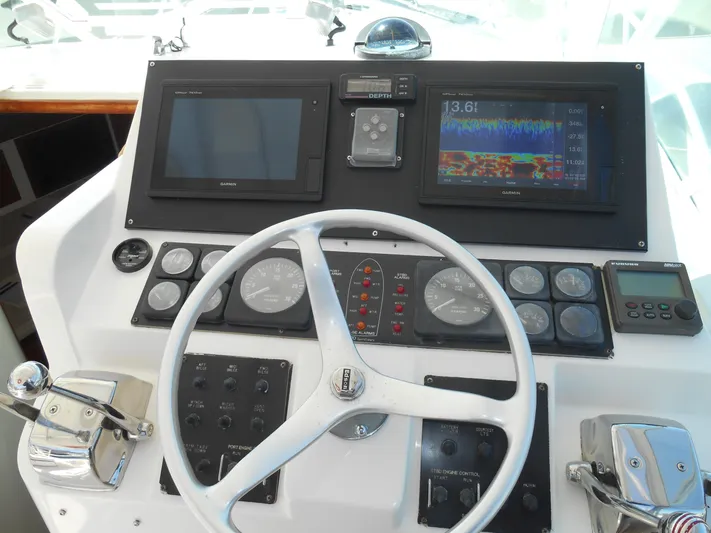 Mistress Yacht Photos Pics 1998 Cabo 31 Express helm with steering wheel, gauges, and navigation screens.