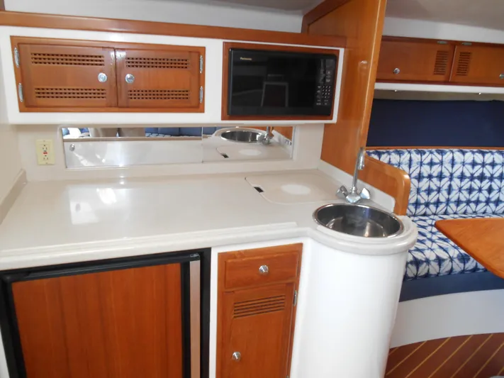 Mistress Yacht Photos Pics 1998 Cabo 31 Express interior with kitchenette, sink, microwave, and seating area.
