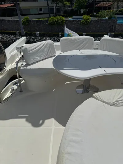 Stella Mia Yacht Photos Pics Azimut 68 Plus 2001 yacht deck with white seating and table, docked near greenery.