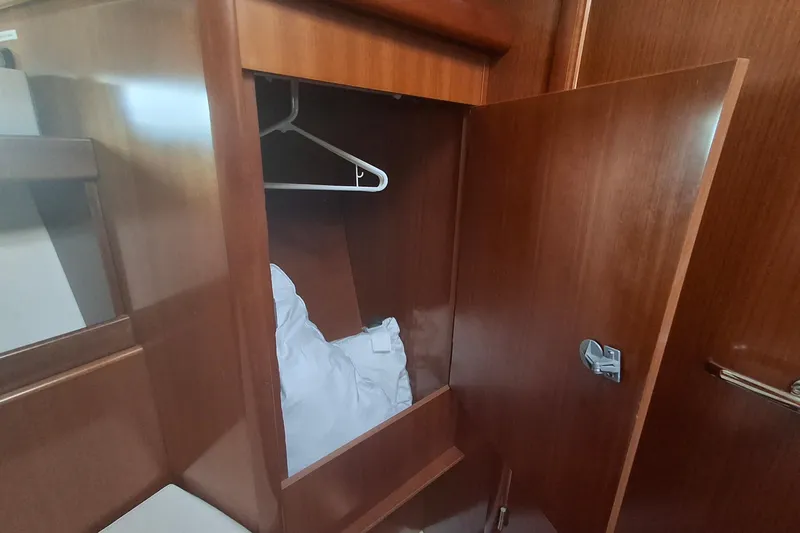 H2o Bungalow Yacht Photos Pics Wooden closet interior on 2006 Beneteau Oceanis 393 yacht, featuring hangers and bedding.