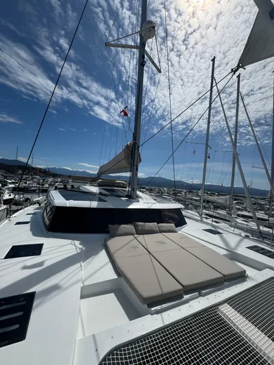 Fp Tanna 47 Yacht Photos Pics 2024 Fountaine Pajot Tanna 47 catamaran with sunbathing area and sails, docked at marina.