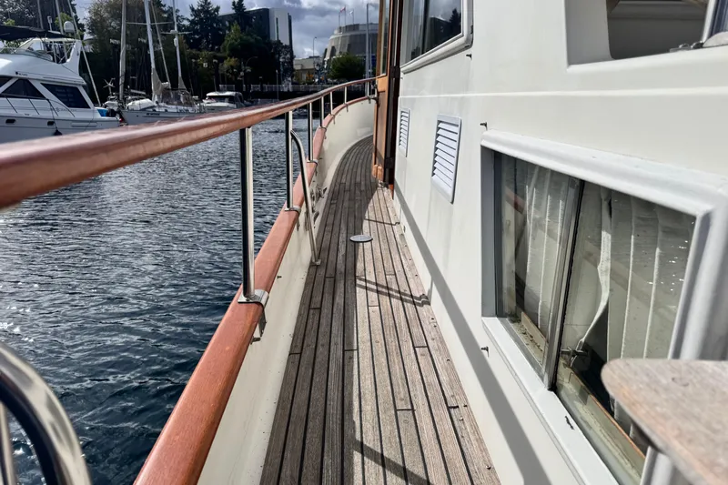  Yacht Photos Pics Side deck view of 1989 Grand Banks 42 yacht, featuring wooden railings and marina backdrop.