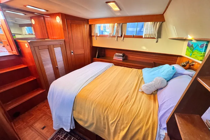  Yacht Photos Pics Cozy bedroom in 1989 Grand Banks 42 yacht with wooden interior and comfortable bedding.