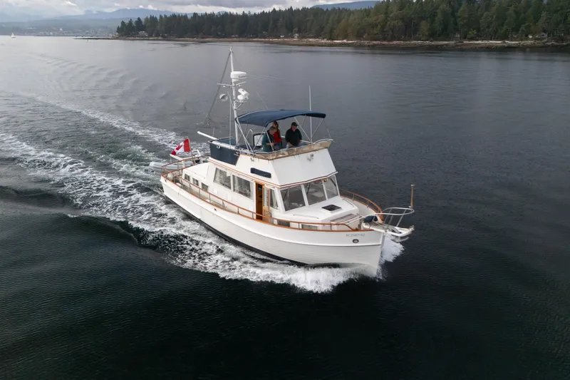  Yacht Photos Pics 1989 Grand Banks 42 cruising on calm waters with scenic forested shoreline.