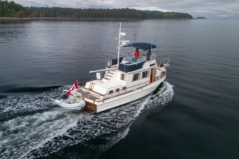  Yacht Photos Pics 1989 Grand Banks 42 yacht cruising on calm waters with forested shoreline.