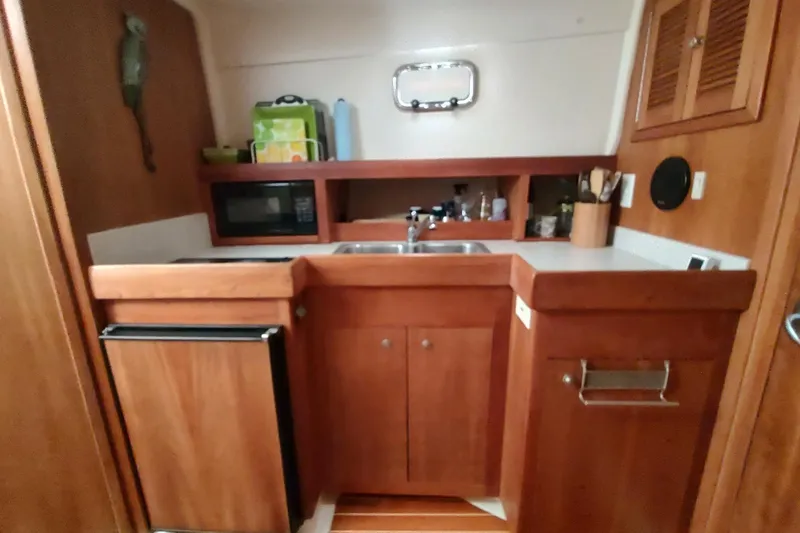 "rosebud" Yacht Photos Pics 2003 Mainship 34 PILOT boat kitchen with wooden cabinets, sink, and microwave.