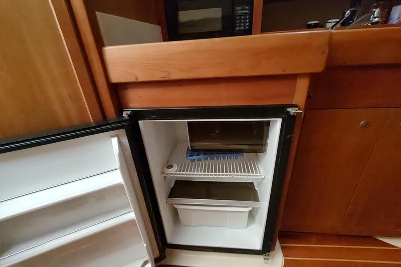 "rosebud" Yacht Photos Pics Open mini fridge in 2003 Mainship 34 PILOT boat galley, wooden cabinetry visible.