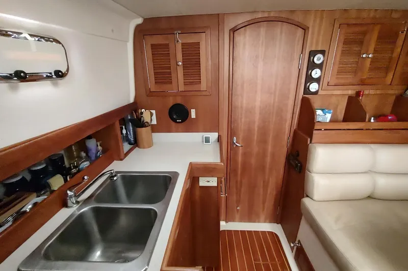 "rosebud" Yacht Photos Pics 2003 Mainship 34 PILOT interior with wooden cabinetry, dual sinks, and cozy seating area.