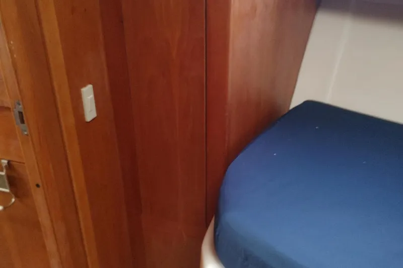 "rosebud" Yacht Photos Pics Interior cabin of 2003 Mainship 34 PILOT with wooden paneling and blue bedding.