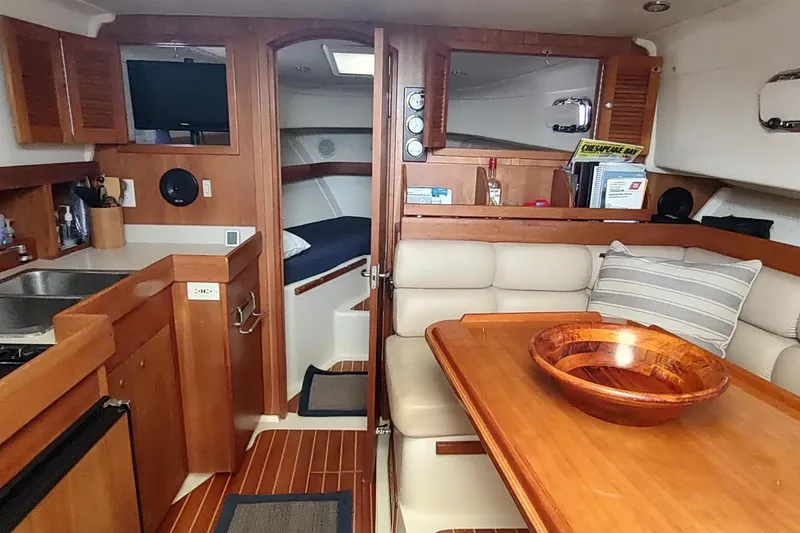 "rosebud" Yacht Photos Pics 2003 Mainship 34 Pilot interior with wood finishes, kitchenette, and cozy seating area.