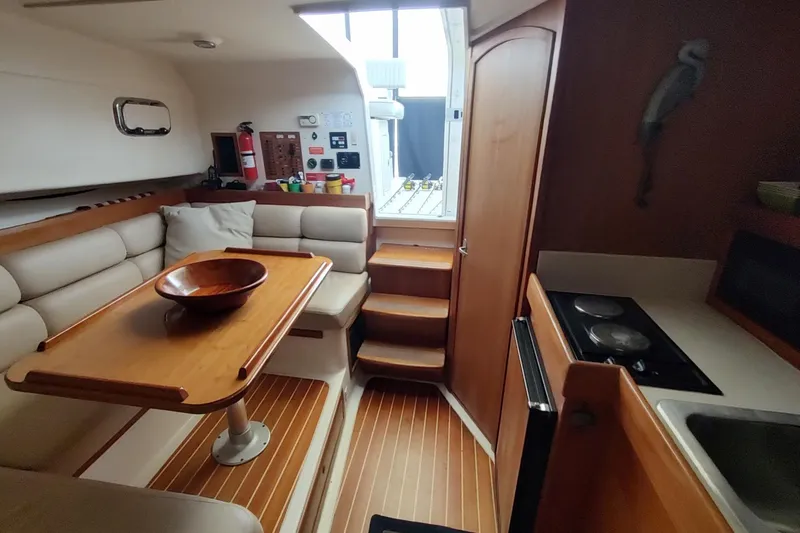 "rosebud" Yacht Photos Pics 2003 Mainship 34 Pilot interior with dining area, kitchenette, and wooden accents.