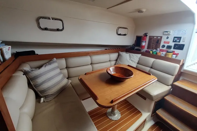 "rosebud" Yacht Photos Pics Cozy interior of 2003 Mainship 34 PILOT with cushioned seating and wooden table.