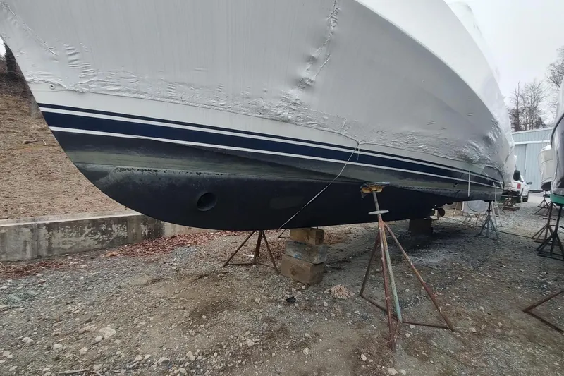 "rosebud" Yacht Photos Pics 2003 Mainship 34 PILOT boat on stands, partially covered, in a dry dock area.