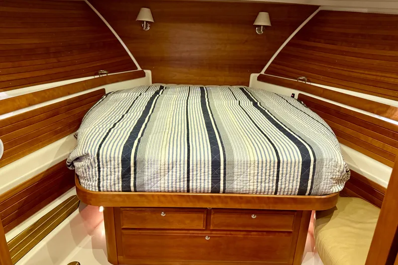 La Dolce Vita Yacht Photos Pics Luxurious cabin interior of 2011 Back Cove 37 yacht with striped bedding and wooden accents.