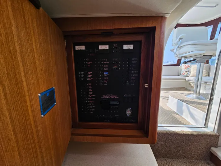 Early Bird Yacht Photos Pics Electrical panel inside a 1998 Ocean Yachts 40, featuring wooden cabinetry and modern seating area.