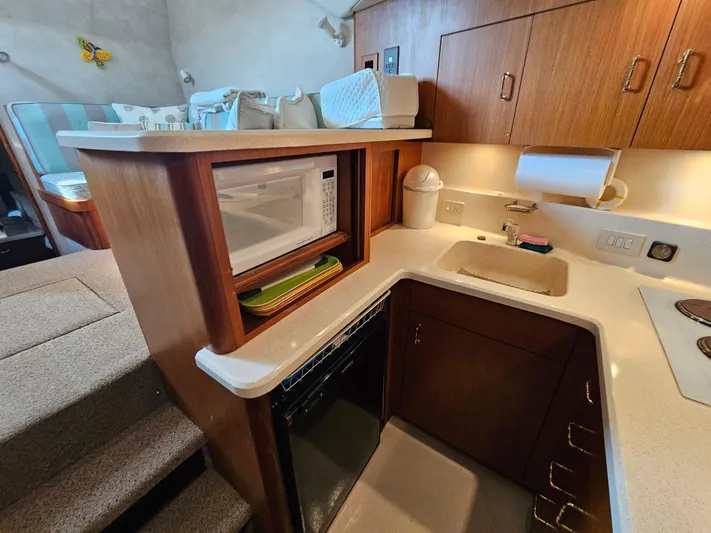 Early Bird Yacht Photos Pics Compact kitchen in a 1998 Ocean Yachts 40, featuring a microwave, sink, and wooden cabinetry.
