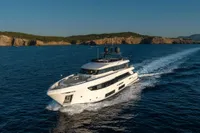Luxurious 2020 Custom Line Navetta 33 yacht cruising on open sea near rocky coastline.