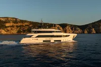 2020 Custom Line Navetta 33 yacht cruising near rocky coastline at sunset.
