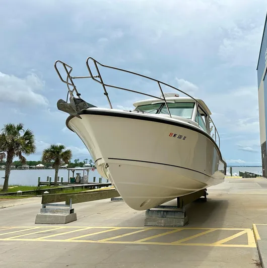 Thomfoolery II Yacht Photos Pics 2016 Boston Whaler 315 Conquest boat on dry dock, with palm trees and water in background.