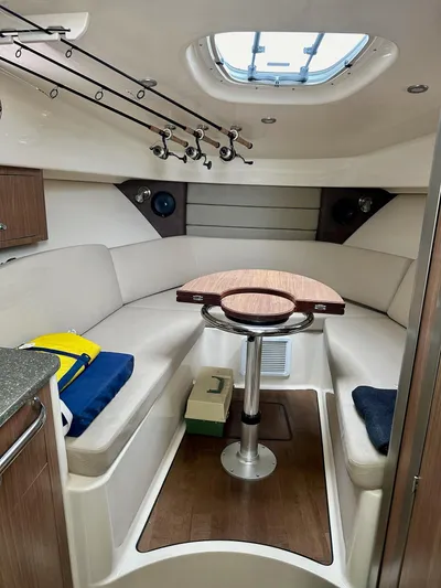 Thomfoolery II Yacht Photos Pics 2016 Boston Whaler 315 Conquest cabin interior with seating, table, and fishing rods.