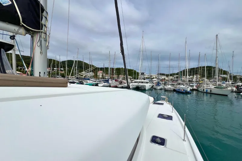 Mocean Yacht Photos Pics Lagoon 42 catamaran in marina, surrounded by sailboats, under cloudy sky.