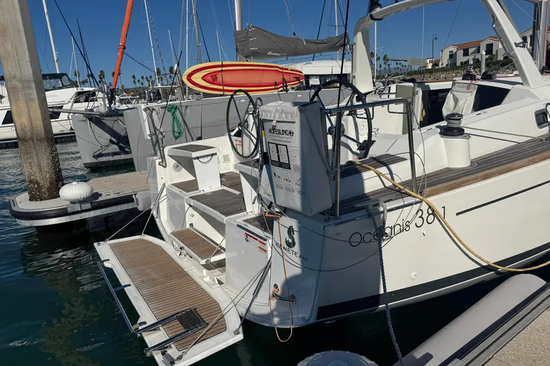  Yacht Photos Pics 2023 Beneteau Oceanis 38.1 yacht docked at marina with surfboard on deck.