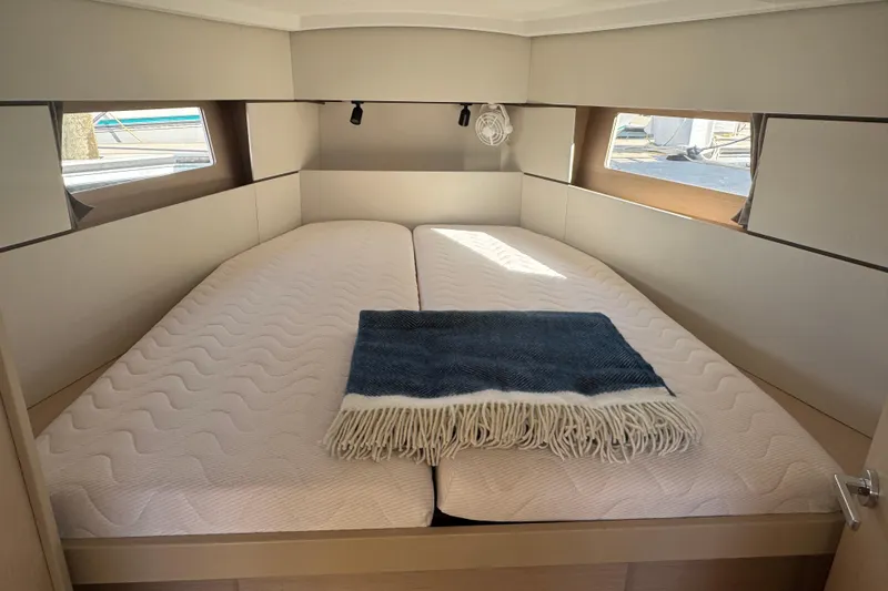  Yacht Photos Pics Cozy cabin interior of 2023 Beneteau Oceanis 38.1 yacht with twin beds and blanket.