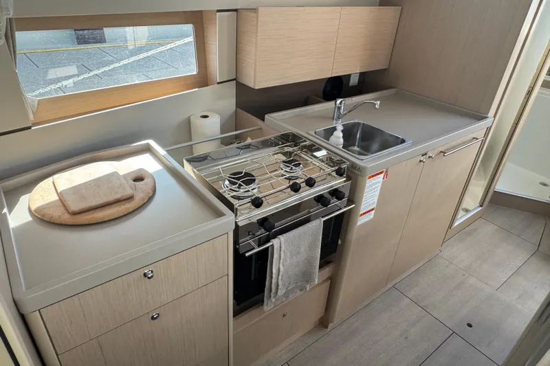  Yacht Photos Pics Modern kitchen in 2023 Beneteau Oceanis 38.1 yacht with stove, sink, and cutting board.