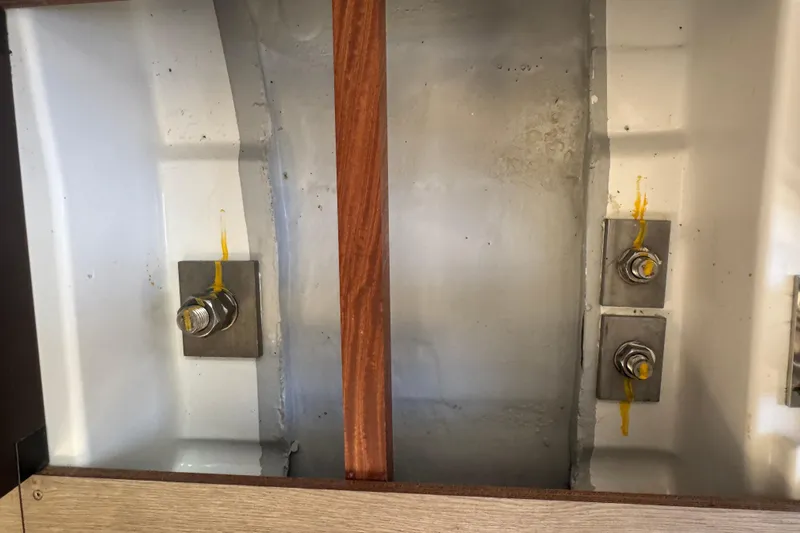  Yacht Photos Pics Interior view of 2023 Beneteau Oceanis 38.1 sailboat hull with visible bolts and wood support.